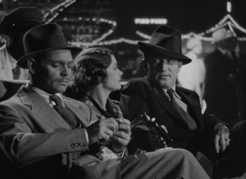 Movie still from “Test Pilot” (1938), directed by Victor Fleming – A man and two women sitting next to each other wearing hats; Medium shot, Low angle
