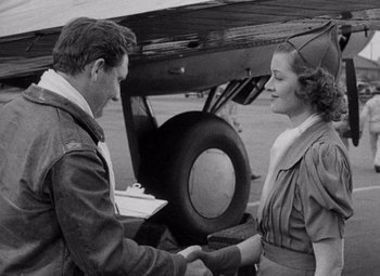 Movie still from “Test Pilot” (1938), directed by Victor Fleming – A man and a woman shaking hands in front of an airplane; Medium shot, Over the shoulder angle
