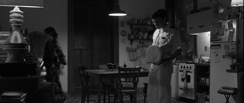 Movie still from “Tetro” (2009), directed by Francis Ford Coppola – A man standing in front of a table holding a tennis racquet; Wide shot, Low angle