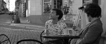 Movie still from “Tetro” (2009), directed by Francis Ford Coppola – A man sitting at an outdoor table with a cup of coffee; Medium shot, Over the shoulder angle