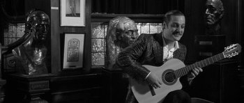 Movie still from “Tetro” (2009), directed by Francis Ford Coppola – A man holding a guitar in front of a statue; Medium shot, Low angle