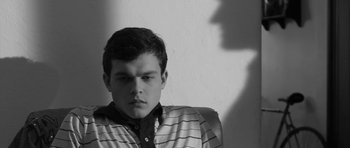 Movie still from “Tetro” (2009), directed by Francis Ford Coppola – A man sitting in a chair with his shadow on the wall behind him; Close Up shot, Low angle