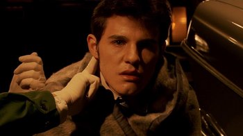 Movie still from “Tetro” (2009), directed by Francis Ford Coppola – A young man in a suit and tie holding his hand to his ear; Close Up shot, High angle