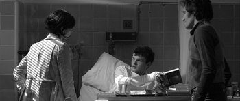 Movie still from “Tetro” (2009), directed by Francis Ford Coppola – A man sitting in a hospital bed holding a book; Medium shot, Over the shoulder angle