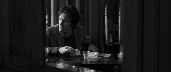 Movie still from “Tetro” (2009), directed by Francis Ford Coppola – A man sitting at a table with a cup of coffee; Medium shot, Over the shoulder angle