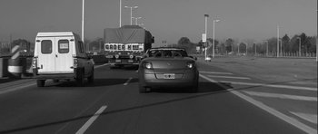 Movie still from “Tetro” (2009), directed by Francis Ford Coppola – A black - and - white photo of cars on a highway; Wide shot, Low angle
