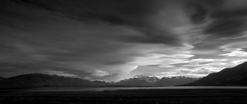 A black and white photo of a cloudy sky and mountains