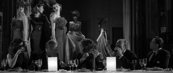 A black and white photo of a group of people sitting at a dinner table