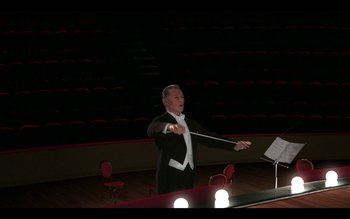 Movie still from “Tetro” (2009), directed by Francis Ford Coppola – A man in a black suit is holding a conductor's baton; Wide shot, Low angle