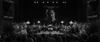 A crowd of people sitting in front of a large screen