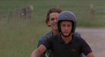 Movie still from “Tex” (1982), directed by Tim Hunter – A man riding a motorcycle next to another man; Close Up shot, Over the shoulder angle