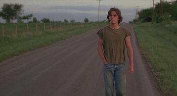 Movie still from “Tex” (1982), directed by Tim Hunter – A man standing on the side of a road; Medium shot, Low angle