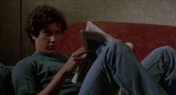 Movie still from “Tex” (1982), directed by Tim Hunter – A man is reading a magazine on the couch; Close Up shot, Over the shoulder angle