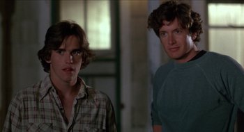 Movie still from “Tex” (1982), directed by Tim Hunter – Two men standing next to each other near a window; Medium shot, Low angle