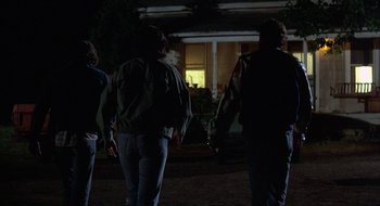 Movie still from “Tex” (1982), directed by Tim Hunter – A group of people standing in the dark; Wide shot, Over the shoulder angle