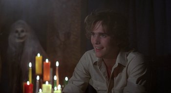 Movie still from “Tex” (1982), directed by Tim Hunter – A man sitting in front of candles in a dark room; Close Up shot, Over the shoulder angle