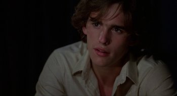 Movie still from “Tex” (1982), directed by Tim Hunter – A man with long hair and a white shirt is looking at the camera; Close Up shot, Over the shoulder angle