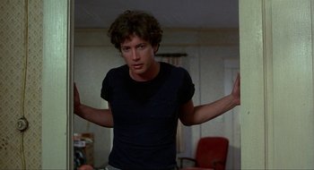 Movie still from “Tex” (1982), directed by Tim Hunter – A man standing in front of a bathroom mirror with his arms outstretched; Medium shot, Low angle