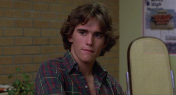 Movie still from “Tex” (1982), directed by Tim Hunter – A young man in a plaid shirt sitting in front of a brick wall; Close Up shot, Over the shoulder angle