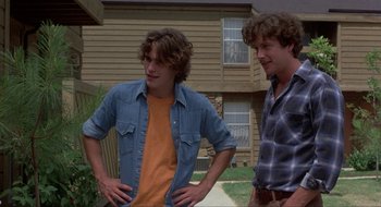 Movie still from “Tex” (1982), directed by Tim Hunter – Two young men standing next to each other in front of a house; Medium shot, Over the shoulder angle