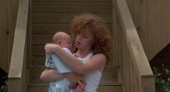 Movie still from “Tex” (1982), directed by Tim Hunter – A woman holding a baby in her arms; Medium shot, Low angle
