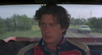 Movie still from “Tex” (1982), directed by Tim Hunter – A person wearing a jacket in a car; Close Up shot, Over the shoulder angle