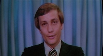Movie still from “Tex” (1982), directed by Tim Hunter – A man in a suit and tie in front of a blue curtain; Close Up shot, Low angle