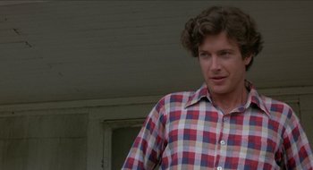 Movie still from “Tex” (1982), directed by Tim Hunter – A man in a plaid shirt standing in front of a building; Close Up shot, Over the shoulder angle