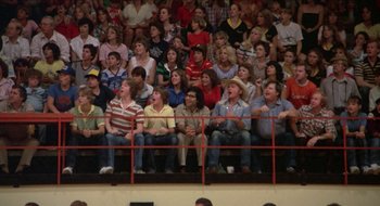 Movie still from “Tex” (1982), directed by Tim Hunter – A group of people sitting in the bleachers watching a game; Wide shot, Low angle
