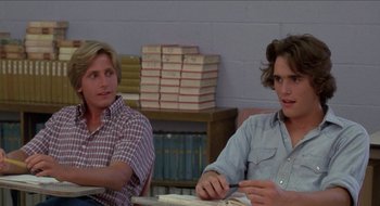 Movie still from “Tex” (1982), directed by Tim Hunter – Two young men sitting at a table in front of stacks of books; Medium shot, Over the shoulder angle