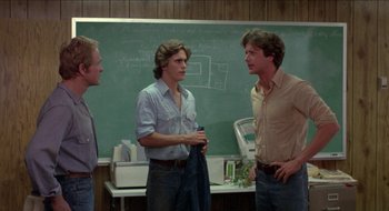 Movie still from “Tex” (1982), directed by Tim Hunter – A group of men standing next to each other in front of a chalkboard; Medium shot, Over the shoulder angle