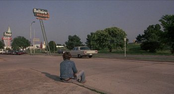 Movie still from “Tex” (1982), directed by Tim Hunter – A man sitting on the side of the road; Wide shot, Over the shoulder angle
