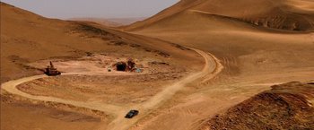 Movie still from “The 33” (2015), directed by Patricia Riggen – A car driving down a dirt road in the middle of the desert; Extreme Wide shot, Overhead angle