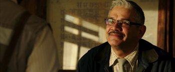 Movie still from “The 33” (2015), directed by Patricia Riggen – An older man wearing glasses and a black jacket; Close Up shot, Low angle