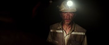 Movie still from “The 33” (2015), directed by Patricia Riggen – A man wearing a hard hat and safety glasses; Close Up shot, High angle