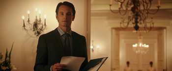 Movie still from “The 33” (2015), directed by Patricia Riggen – A man in a suit and tie holding a folder; Medium shot, Over the shoulder angle