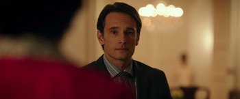 Movie still from “The 33” (2015), directed by Patricia Riggen – A person wearing a suit and tie; Close Up shot, Over the shoulder angle