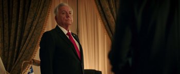 Movie still from “The 33” (2015), directed by Patricia Riggen – An older man wearing a suit and red neck tie; Close Up shot, Low angle