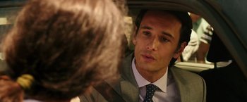 Movie still from “The 33” (2015), directed by Patricia Riggen – A person wearing a suit in a car; Close Up shot, Over the shoulder angle