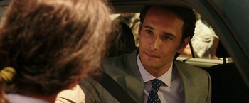 Movie still from “The 33” (2015), directed by Patricia Riggen – A person wearing a suit in a car; Close Up shot, Over the shoulder angle