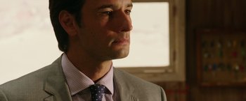 Movie still from “The 33” (2015), directed by Patricia Riggen – A person wearing a suit and tie; Close Up shot, Over the shoulder angle