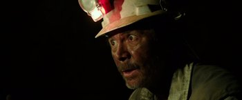 Movie still from “The 33” (2015), directed by Patricia Riggen – An old man wearing a hard hat with a light on his head; Close Up shot, Overhead angle