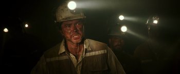 Movie still from “The 33” (2015), directed by Patricia Riggen – A man in a hard hat with a light on his head; Medium shot, Over the shoulder angle