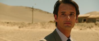 Movie still from “The 33” (2015), directed by Patricia Riggen – A person wearing a suit and tie; Close Up shot, Over the shoulder angle