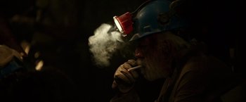 Movie still from “The 33” (2015), directed by Patricia Riggen – A man in a hard hat smokes a cigarette; Close Up shot, High angle