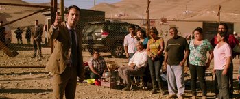 Movie still from “The 33” (2015), directed by Patricia Riggen – A group of people standing in a dirt field; Medium shot, Over the shoulder angle