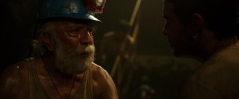 Movie still from “The 33” (2015), directed by Patricia Riggen – An old man with a beard and a hard hat on; Close Up shot, Over the shoulder angle