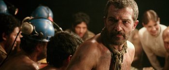 Movie still from “The 33” (2015), directed by Patricia Riggen – A man with a beard is standing next to other men; Close Up shot, Over the shoulder angle