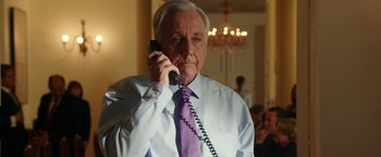 Movie still from “The 33” (2015), directed by Patricia Riggen – An older man wearing a purple tie talking on a phone; Close Up shot, Low angle