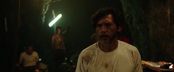 Movie still from “The 33” (2015), directed by Patricia Riggen – A man in a white shirt is in the dark; Medium shot, Over the shoulder angle